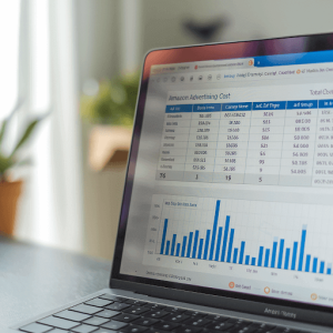 A laptop screen displaying a spreadsheet with various metrics about Amazon Advertising Cost